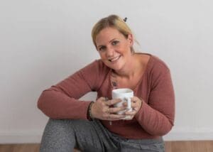 Joelle sat on the floor holding a mug of tea